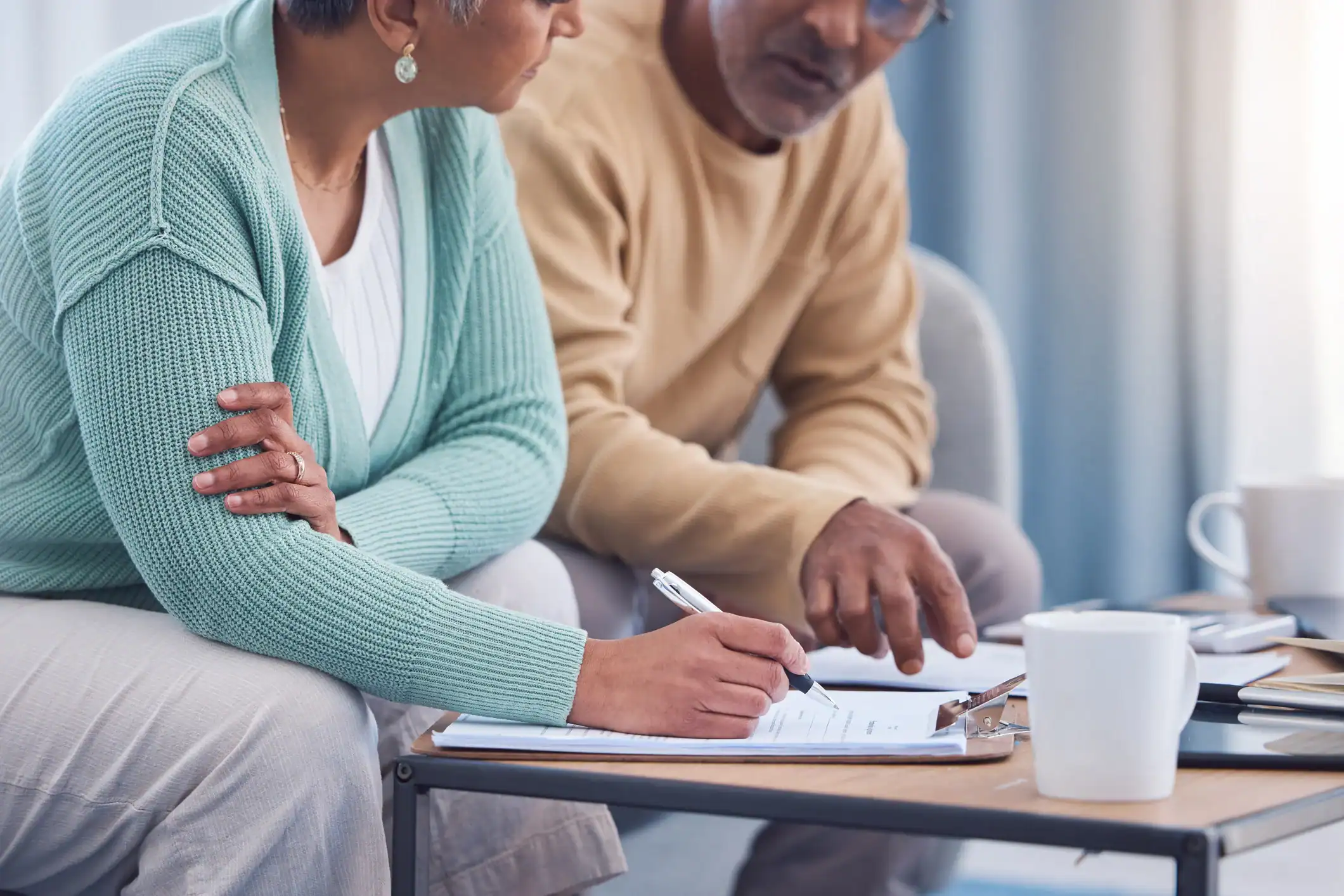 Older couple reviewing and signing documents at a table