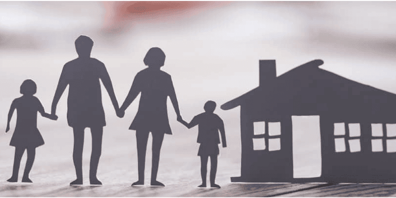 a family of four made of gray paper next to a paper house.